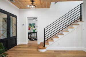 Modern home interior with wooden staircase and black railing.