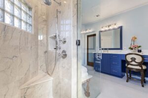 Modern bathroom with glass shower and blue cabinetry.