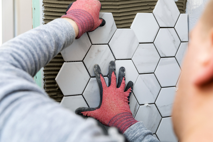 Worker installing hexagonal marble wall tiles